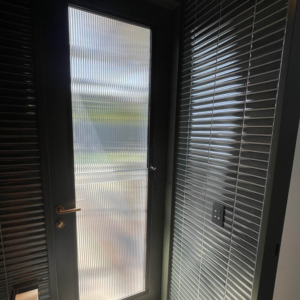 Modern glass door with reeded glass film in modern powder room