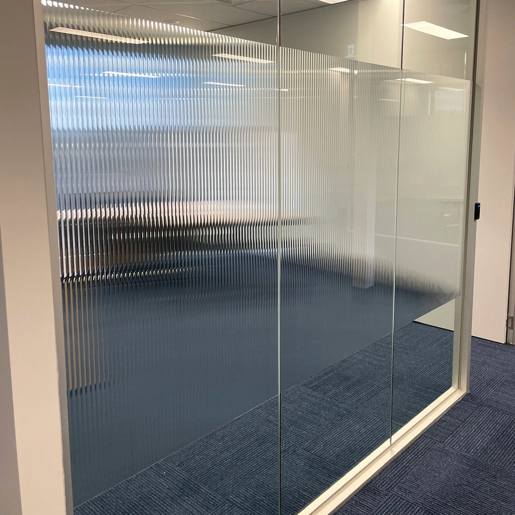 Glass office partition with reeded glass film for privacy band