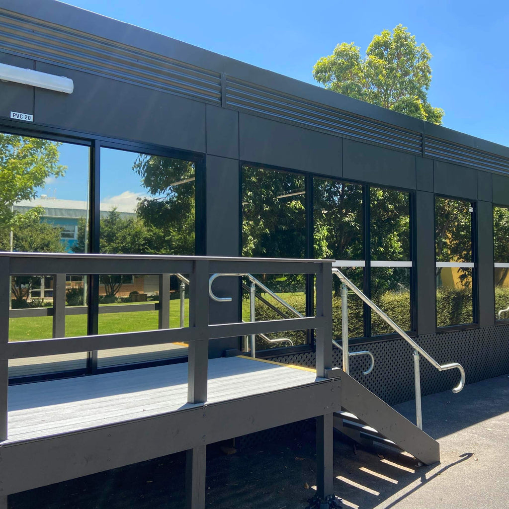 School building exterior with a ramp and handrails on a sunny day