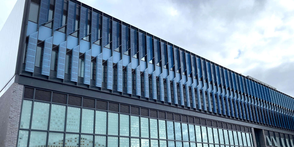 Modern building facade with blue glass panels and a cloudy sky.