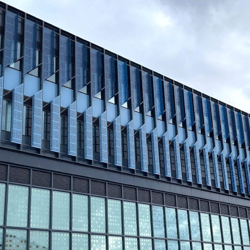 Modern building facade with geometric window design against a cloudy sky